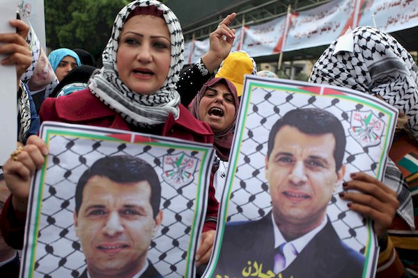 غزة: فلسطينية ترفع صوراً للقيادي الفلسطيني محمد دحلان 
