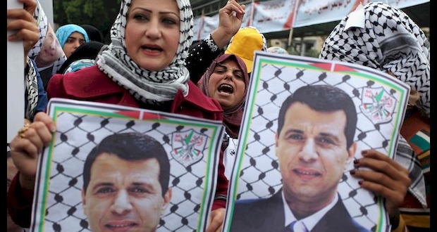غزة: فلسطينية ترفع صوراً للقيادي الفلسطيني محمد دحلان 